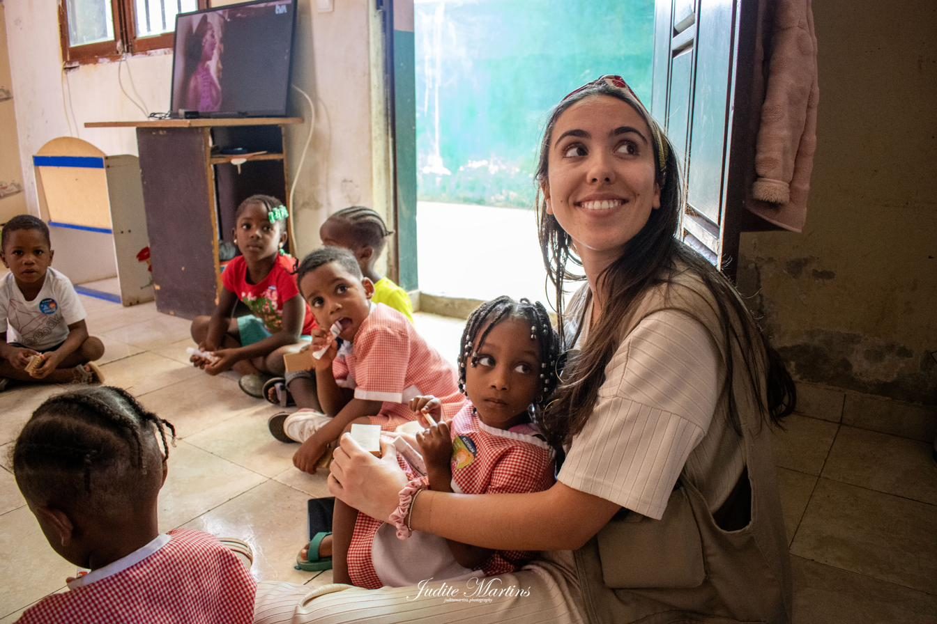 Voluntária da World Needs sentada com crianças em Cabo Verde, num momento afetuoso