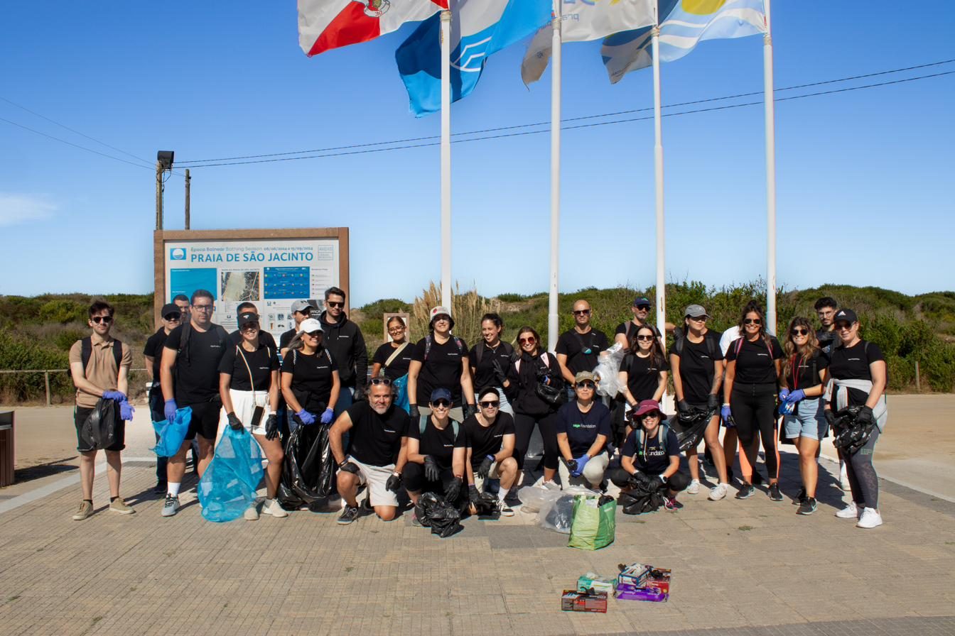 Grupo de voluntários junto às bandeiras da Praia de São Jacinto, com sacos de lixo recolhido
