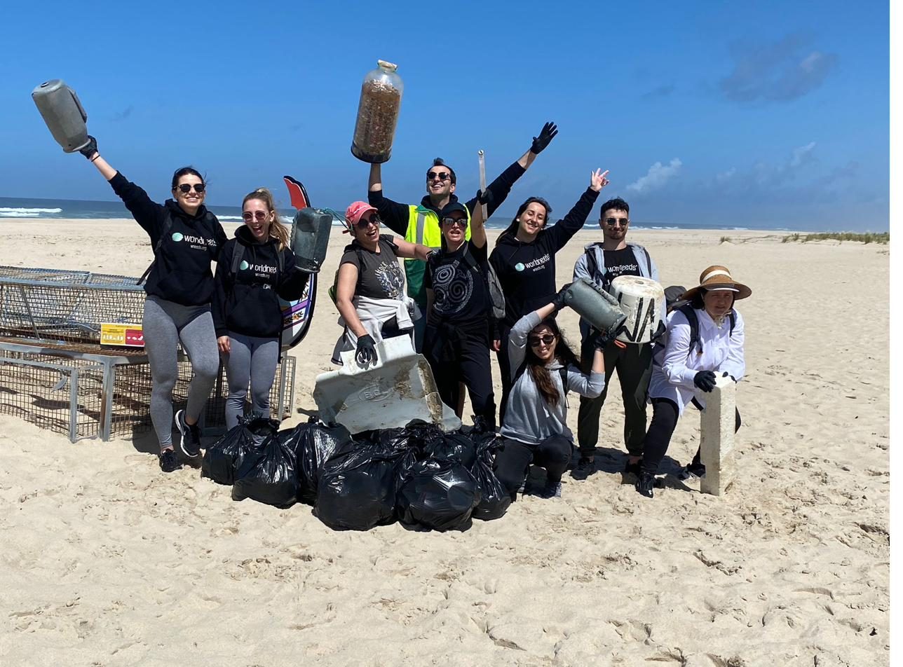 Voluntários a celebrar com sacos de lixo recolhido na praia