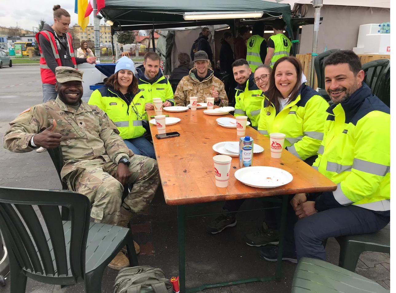 Voluntários e militares reunidos junto a uma tenda de apoio humanitário em Przemyśl, Polónia